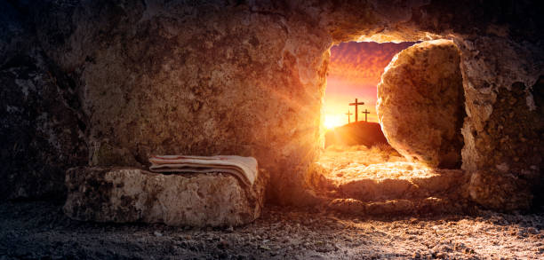 Empty tomb of Jesus at sunrise with crosses in background
